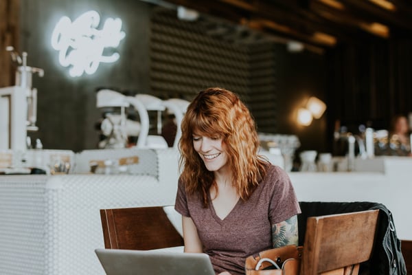 woman smiling at computer in coffee shop